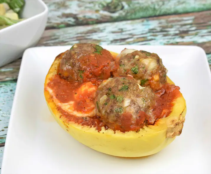 spaghetti squash boat with cheese stuffed meatballs on white plate
